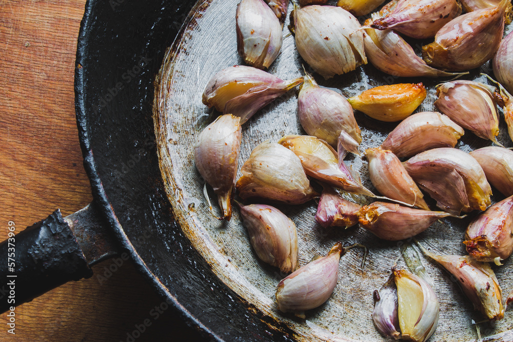 baked slices of garlic in the shell in an old pan, garlic is baked ...