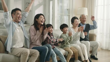 Wall Mural - happy three generation asian family sitting on couch in a row at home watching tv