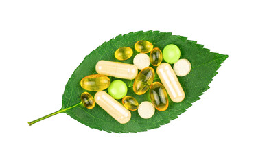 Variety of dietary supplement pills on fresh green leaf isolated on transparent background, top view. Alternative medicine concept