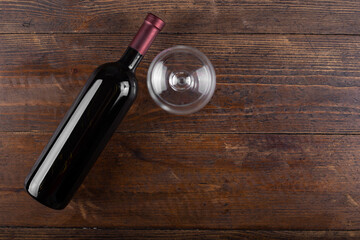 Wall Mural - Bottle with red wine and an empty glass, on a wooden background. View from above.