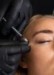 Closeup of Caucasian woman gets botox cosmetic injection in eye area. Beauty physician inserts needle of syringe into face of beautiful female. Cosmetologist, aesthetic medicine. Vertical