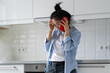 © DimaBerlin - Sad depressed young Asian woman standing at home talking phone, hearing bad news, calling psychologist to receive mental health support, frustrated female making phone call, needs someone to talk to.