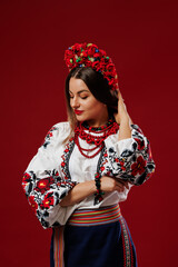 Wall Mural - Portrait of ukrainian woman in traditional ethnic clothing and floral red wreath on viva magenta studio background. Ukrainian national embroidered dress call vyshyvanka. Pray for Ukraine