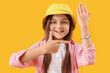 © Pixel-Shot - Little girl pointing at wristwatch on yellow background