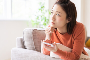 Wall Mural - 部屋でスマホを見る女性　考える