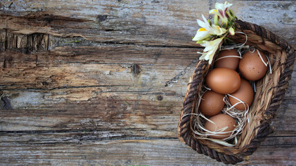 Wall Mural - Background easter. A basket with eggs stands on a wooden rustic background. Copy space. Flat Lay.