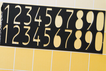 Sticker - old black paper stencil with numbers on yellow paper pad sheet with paint-chip pattern and coloration