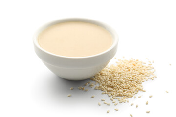 Ceramic bowl of tasty tahini and sesame seeds on white background