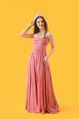 Wall Mural - Beautiful young woman in stylish prom dress and tiara on yellow background