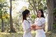 © Natee Meepian - Attractive Asian woman giving a beautiful flower bouquet to her friend, in the park