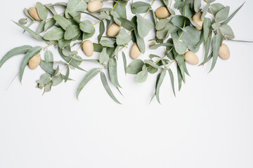 Wall Mural - Beautiful flat lay easter composition of wooden easter eggs and eucalyptus leaves on a white background, with space for copy.