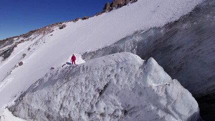 Wall Mural - The guy in red is standing on top of the glacier. Frozen moraine lake in the mountains. Lots of snow. Aerial view from a drone of people, mountains and trails in the snow. The ice is breaking down