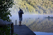 © Cavan Images - Mature man takes photo on dock in lake at sunrise