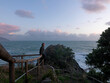 © Cavan Images - Man balances on railing above sea at sunset