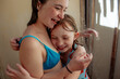 © Cavan Images - Sisters hugging in outdoor shower after swimming