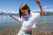 © Cavan Images - Young girl dancing on lake shore near snowy mountains