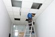 © New Africa - Installing ceiling lighting. Electrician working on step ladder in room