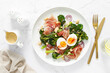 Easter egg salad with prosciutto and broccolini on white background, top view. Easter salad with boiled egg
