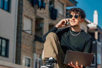 Wall Mural - young man in the street outdoors with laptop and mobile phone