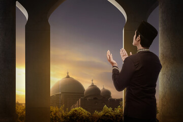 Wall Mural - Muslim man standing while raised hands and praying