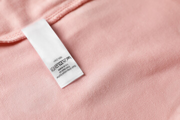 Poster - Clothing label on beautiful pink garment, top view. Space for text