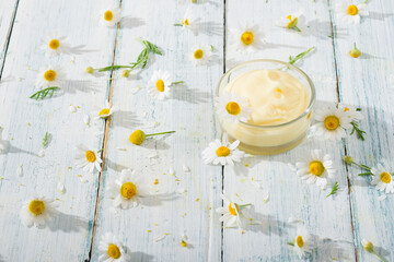 Wall Mural - chamomile flowers and baby cream on faded white wooden table