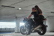 © perfectlab - Young couple hugging sitting on a motorcycle in underground parking garage