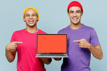 Wall Mural - Young fun couple two friends IT men wear casual clothes together hold use work point on laptop pc computer with blank screen workspace area isolated on pastel plain light blue cyan background studio.