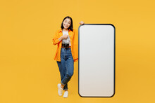 Young Woman Wear Summer Clothes Point On Big Huge Blank Screen Mobile Cell Phone Isolated On Plain Yellow Background. Tourist Travel Abroad In Free Time Rest Getaway. Air Flight Trip Journey Concept.