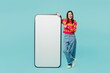 © ViDi Studio - Full body young woman in bright casual clothes point index finger on big huge blank screen mobile cell phone smartphone with workspace mockup area isolated on plain pastel light blue cyan background