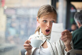 Fototapeta Zwierzęta - Pretty, young woman baffled with the bill in a coffeeshop/restaurant