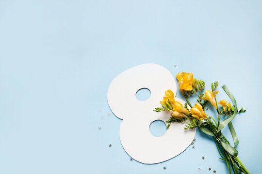 number 8 shape layout with yellow flowers bouquet on blue background. copy space. top view. concept 