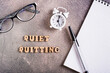Quiet quitting concept. Wooden letters, stationery and alarm clock. Top view.