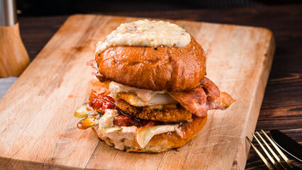 Wall Mural - American food burger with fried chicken, bacon, pickled cucumbers, tomatoes, mustard and sauce.