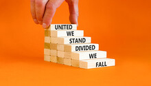 United Or Divided Symbol. Concept Words United We Stand Divided We Fall On Wooden Blocks. Beautiful Orange Table Orange Background. Businessman Hand. Business United Or Divided Concept. Copy Space.