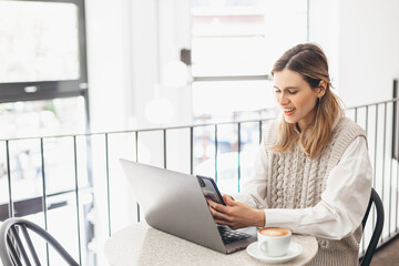 Happy woman using laptop and smartphone at cafe. Smiling woman using smart phone for business, online shopping, transfer money, financial, internet banking, make selfie in coffee shop cafe