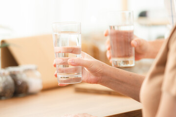 Poster - Family health care in house concept, Asian senior elderly couple drink a glass of water in kitchen room at home, Mature older thirsty grandparent holding clean mineral natural in glass, peace of mind