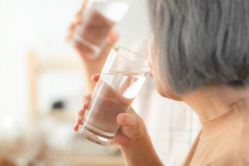 Poster - Family health care in house concept, Asian senior elderly couple drink a glass of water in kitchen room at home, Mature older thirsty grandparent holding clean mineral natural in glass, peace of mind