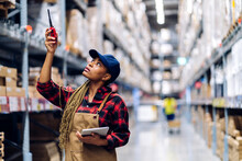 Portrait Of Smiling African American Engineer Woman Order Details Checking Goods And Supplies On Shelves With Goods Background In Warehouse.logistic And Business Export