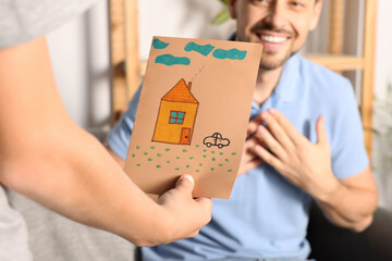 Wall Mural - Happy man receiving greeting card from his son at home, closeup