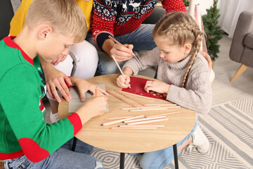 Wall Mural - Cute children with their parents making beautiful Christmas greeting cards at home