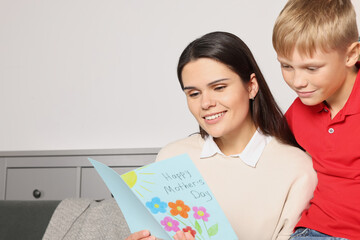 Wall Mural - Happy woman receiving greeting card from her son at home