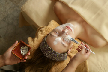 Young woman at natural beauty spa having facial treatment. Relaxation, detoxification, exfoliation of skin rejuvenation concept.