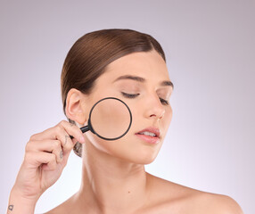 Woman, magnifying glass and face in studio for beauty, cosmetics and dermatology. Facial magnifier, female model and check skincare, aesthetic wellness and inspection for acne, laser and search pores