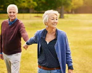 Wall Mural - Romance, retirement and old couple holding hands in field, walking in nature and happy smile on grass. Peace, senior man and woman on romantic walk in park, health and love on holiday in countryside.