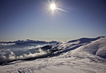 Poster - Bright sun above snowy mountain slopes and clouds landscape photo. Ski resort. Nature scenery photography. Ambient light. High quality picture for wallpaper, travel blog, magazine, article