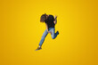 Full body young caucasian man wearing black t-shirt jumping high pretend playing guitar doing hand gesture isolated on yellow color background. People lifestyle