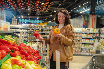 Wall Mural - a woman chooses sweet peppers in a supermarket