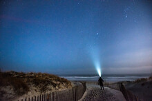 Woman With Headlamp Looking At Sky At Beach At Night, Newport, Rhode Island, USA