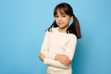 Wall Mural - Photo of attractive little girl look empty space folded arms wear sweater isolated on blue color background